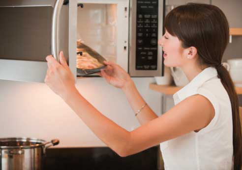 woman cooking food in microwave